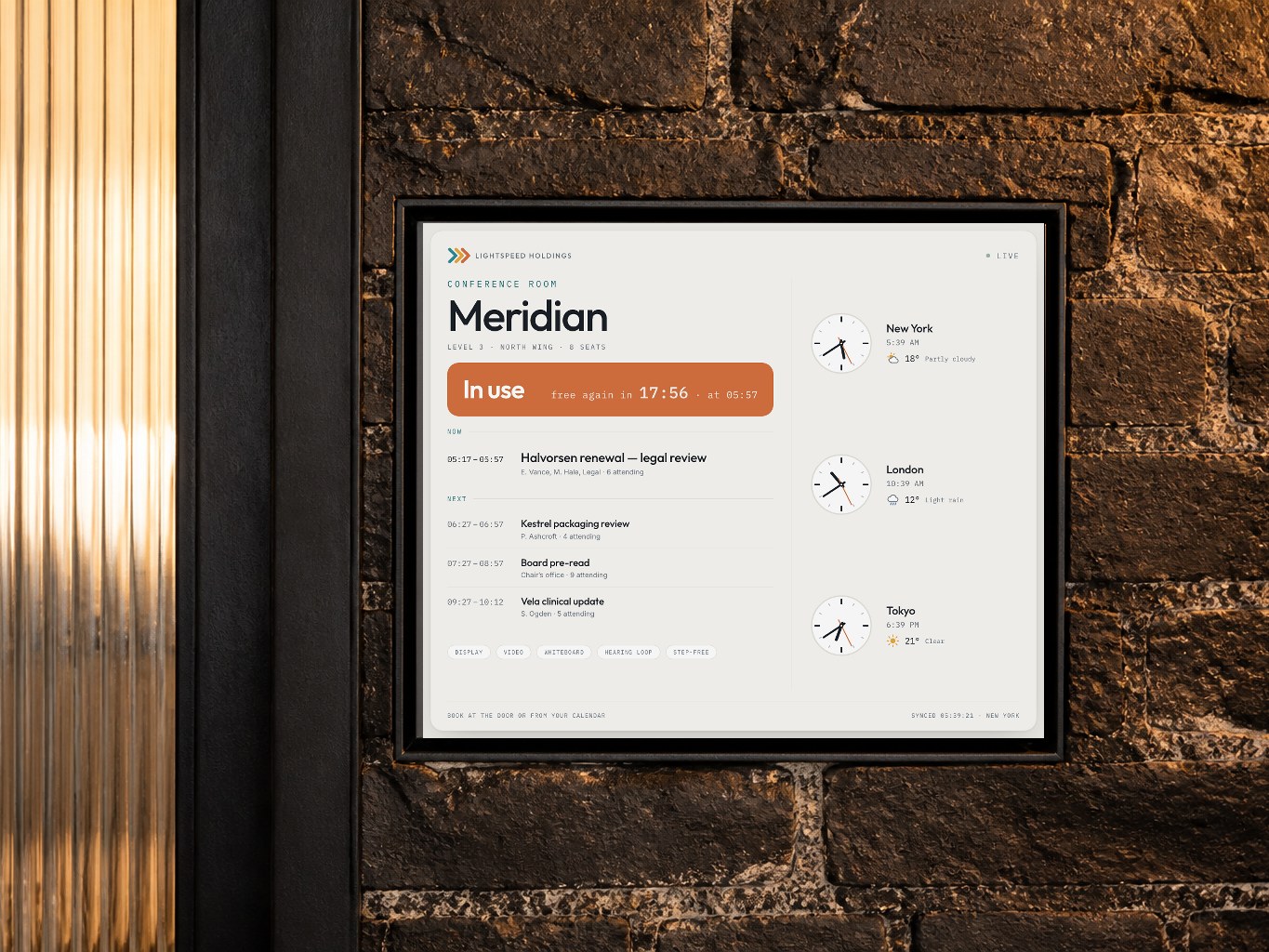 The Meridian room panel, recessed into the brick beside the door, showing the room in use and what is next.